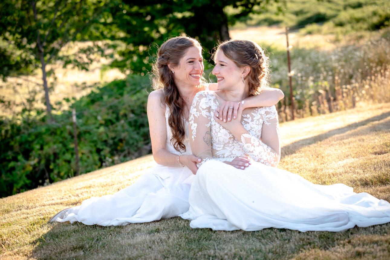 Brides embrace at summer wedding in Oregon captured by premiere wedding photographer elle james