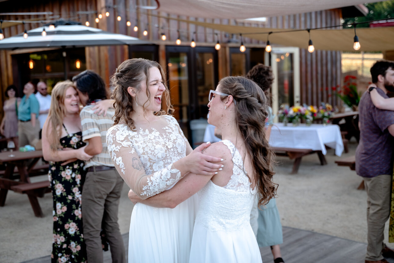 lesbian brides laugh and embrace at wedding
