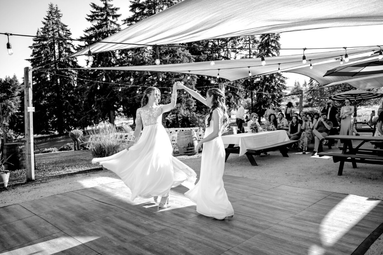 black and white image of two brides dancing and spinning on the dance floor at their summer wedding