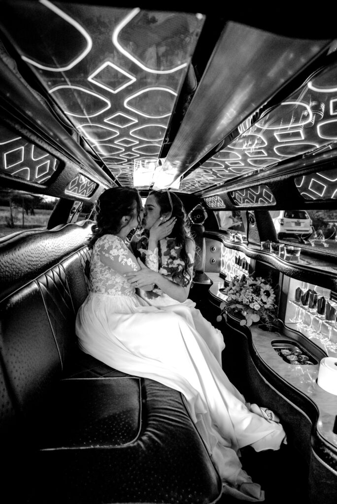 two brides kiss in the limo as they head off to their honeymoon. Black and white image